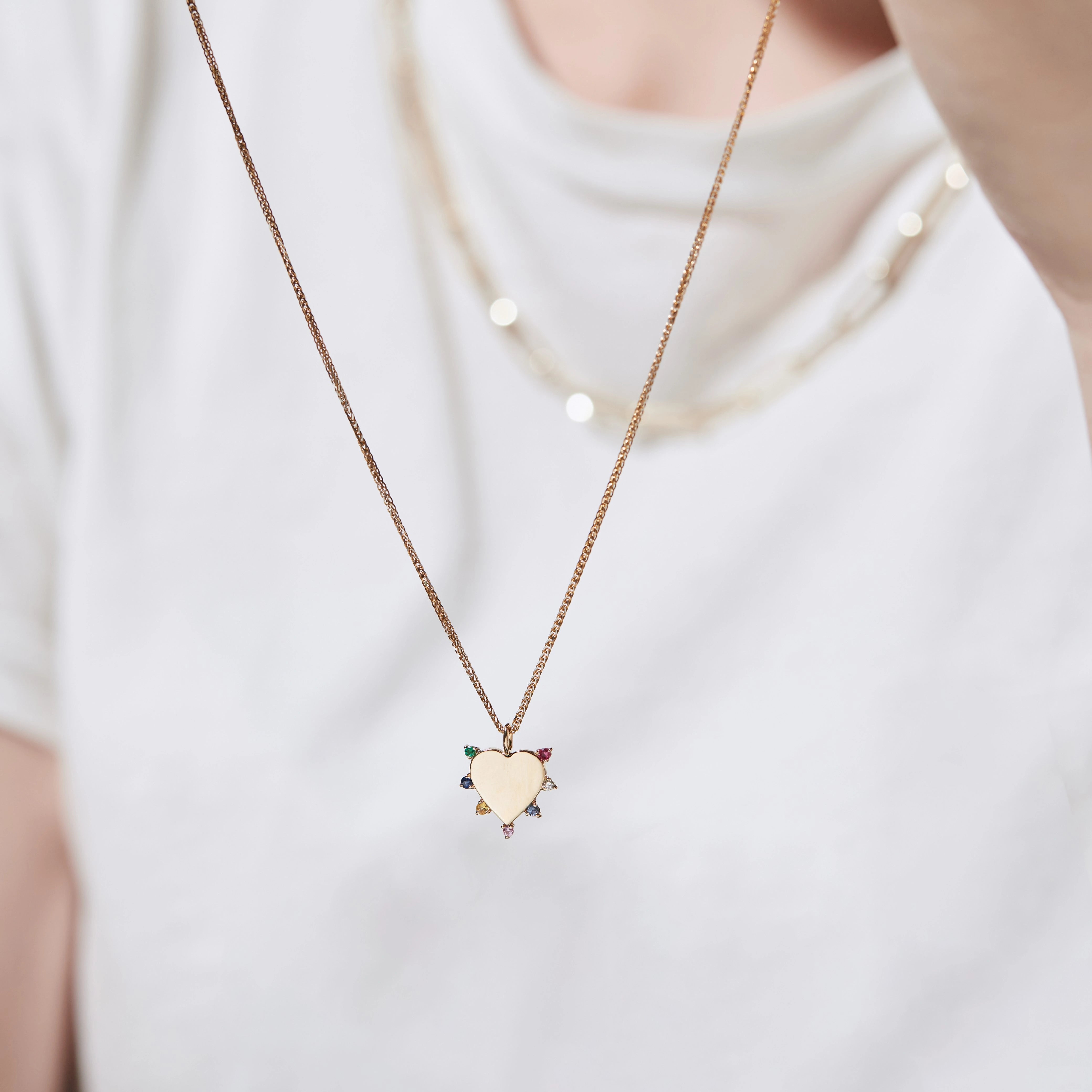Necklace with a heart-shaped pendant worn by a person on a white background