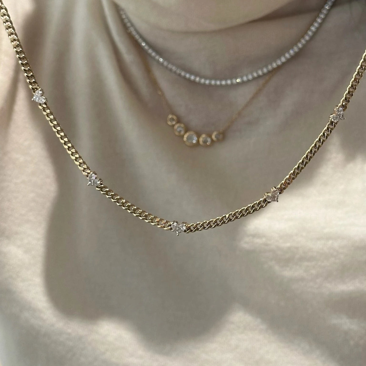 Yellow gold cuban necklace with heart shape diamonds on beige fabric background