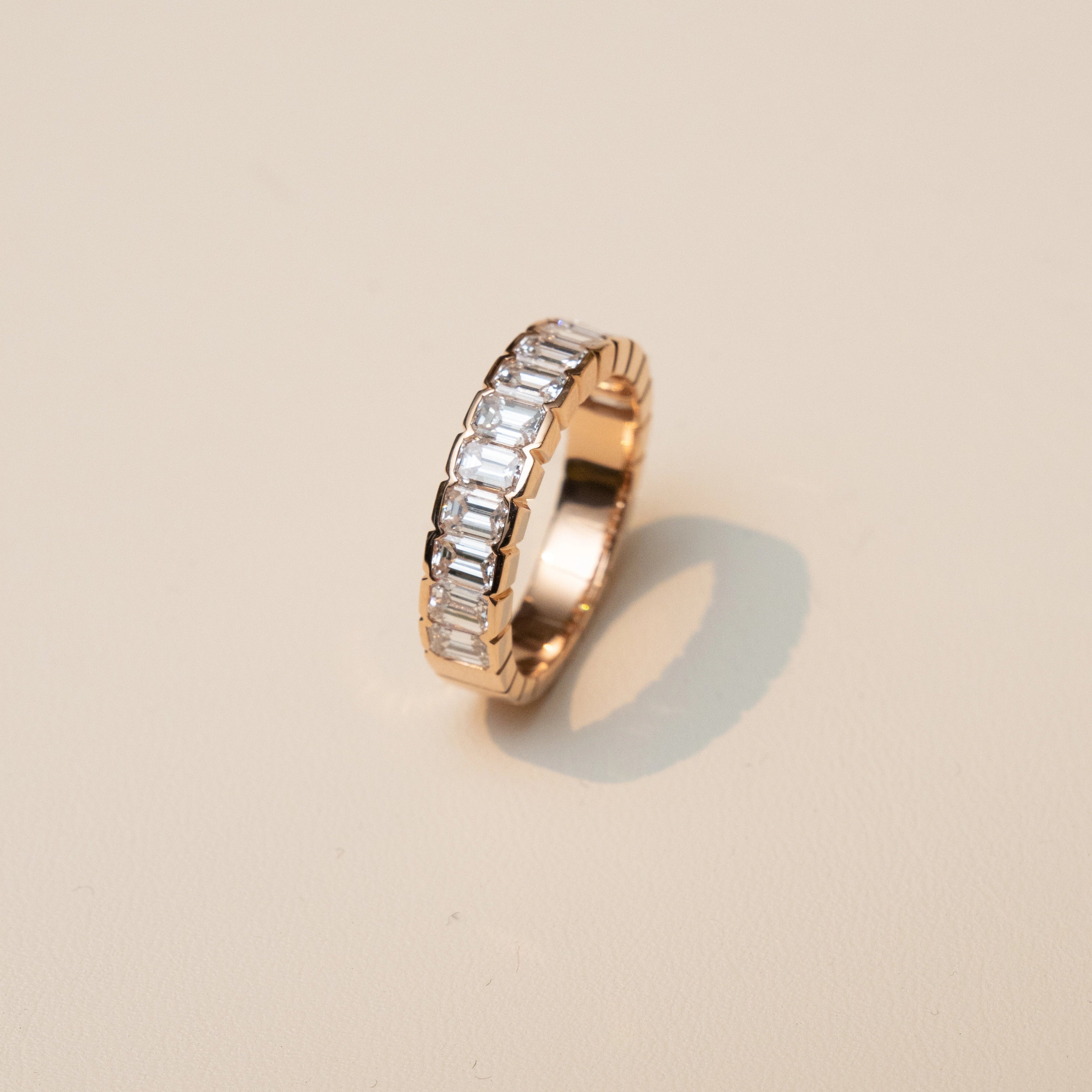 Rose gold ring with embedded stones on a beige background