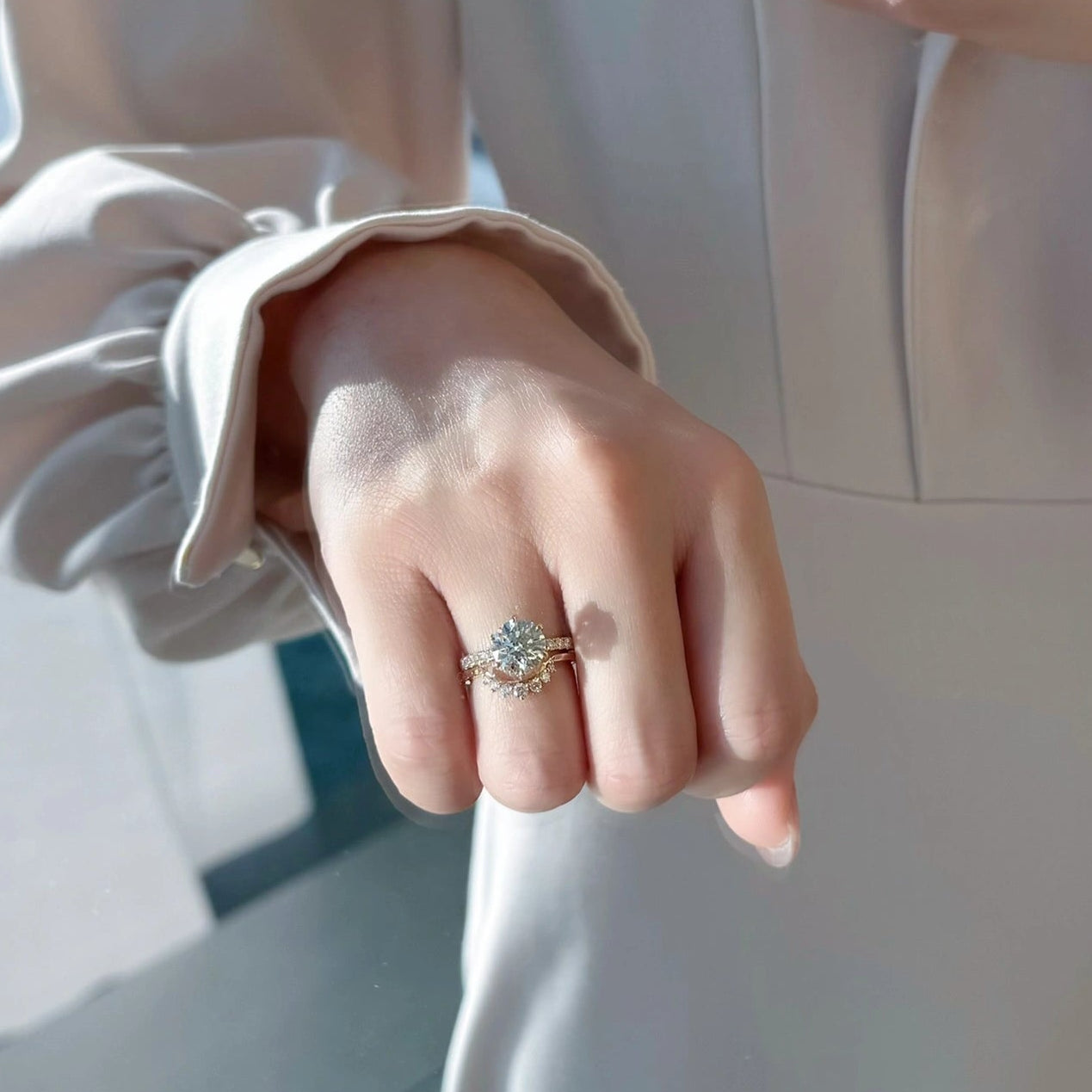 Close-up of a hand wearing a ring with a diamond, against indoor background