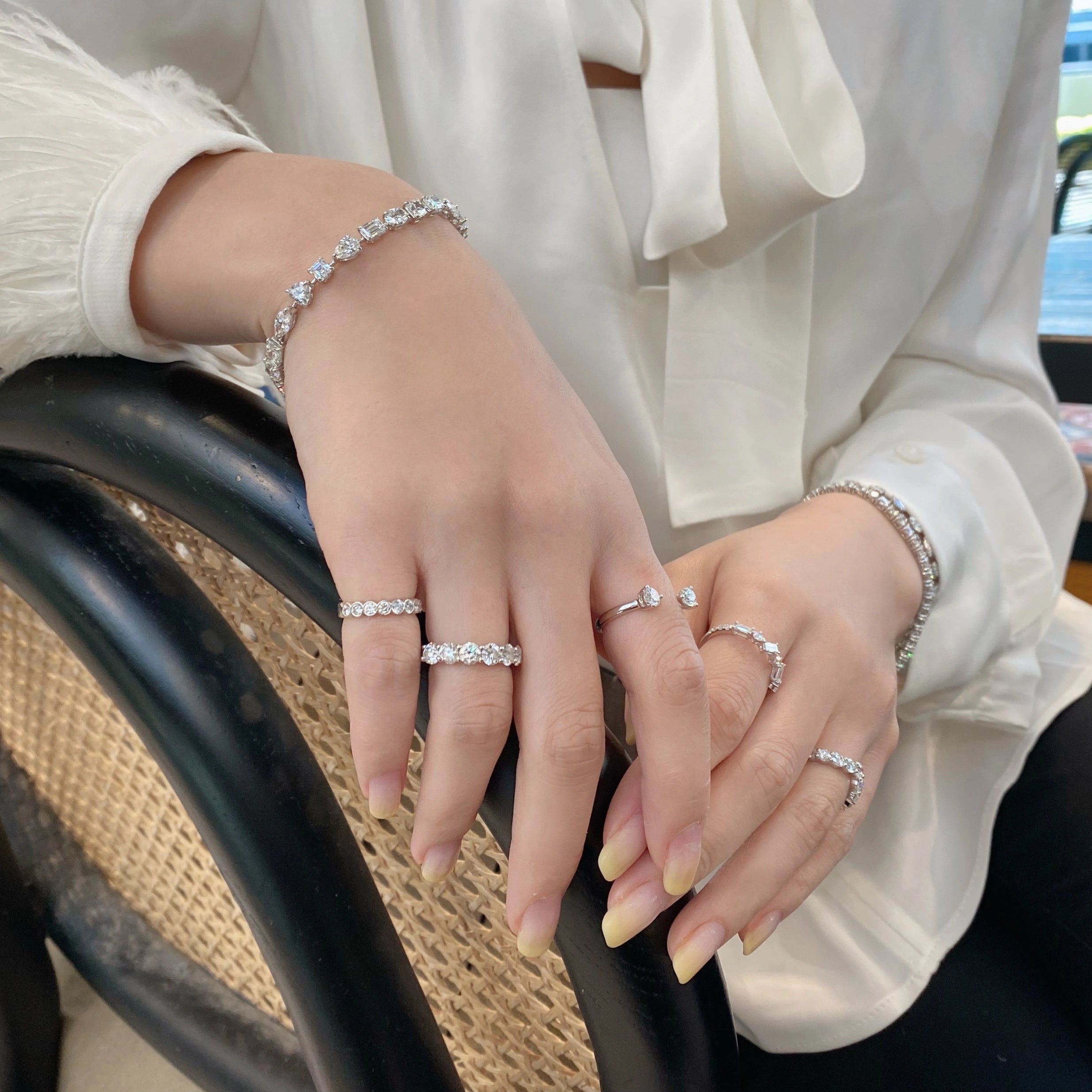 Close-up of hands wearing multiple diamond rings and bracelets.