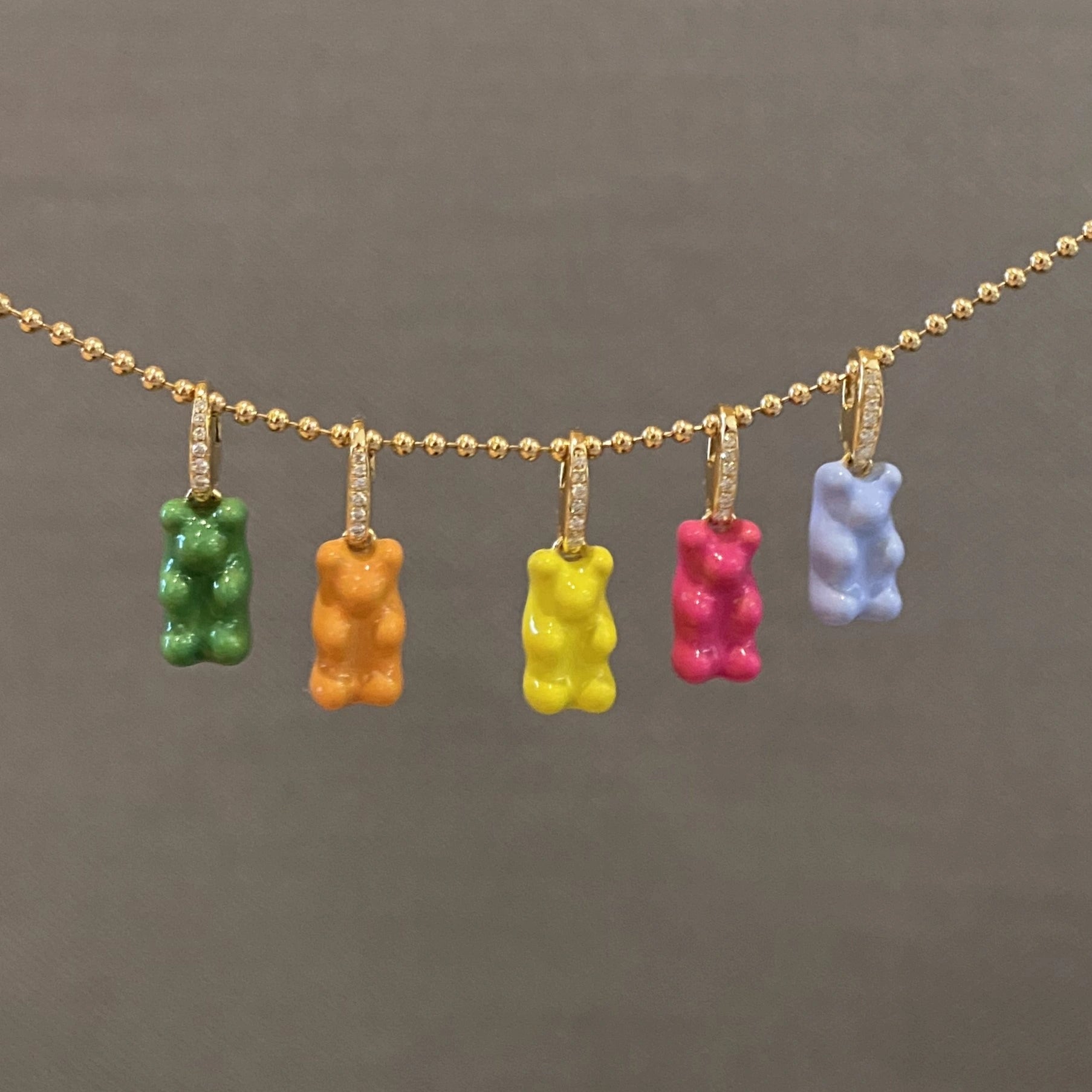Necklace with colorful gummy bear pendants on a gold chain against a gray background