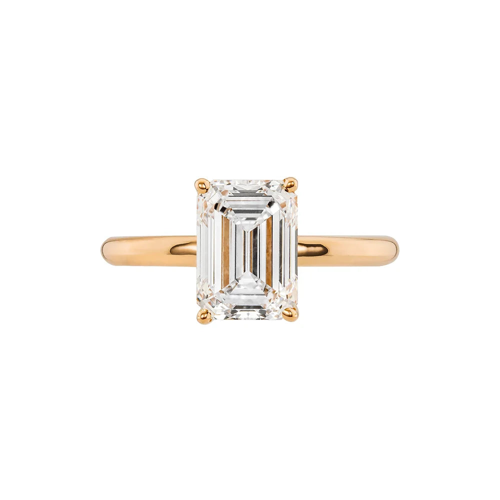 Rose gold emerald cut solitaire skinny band on white background.