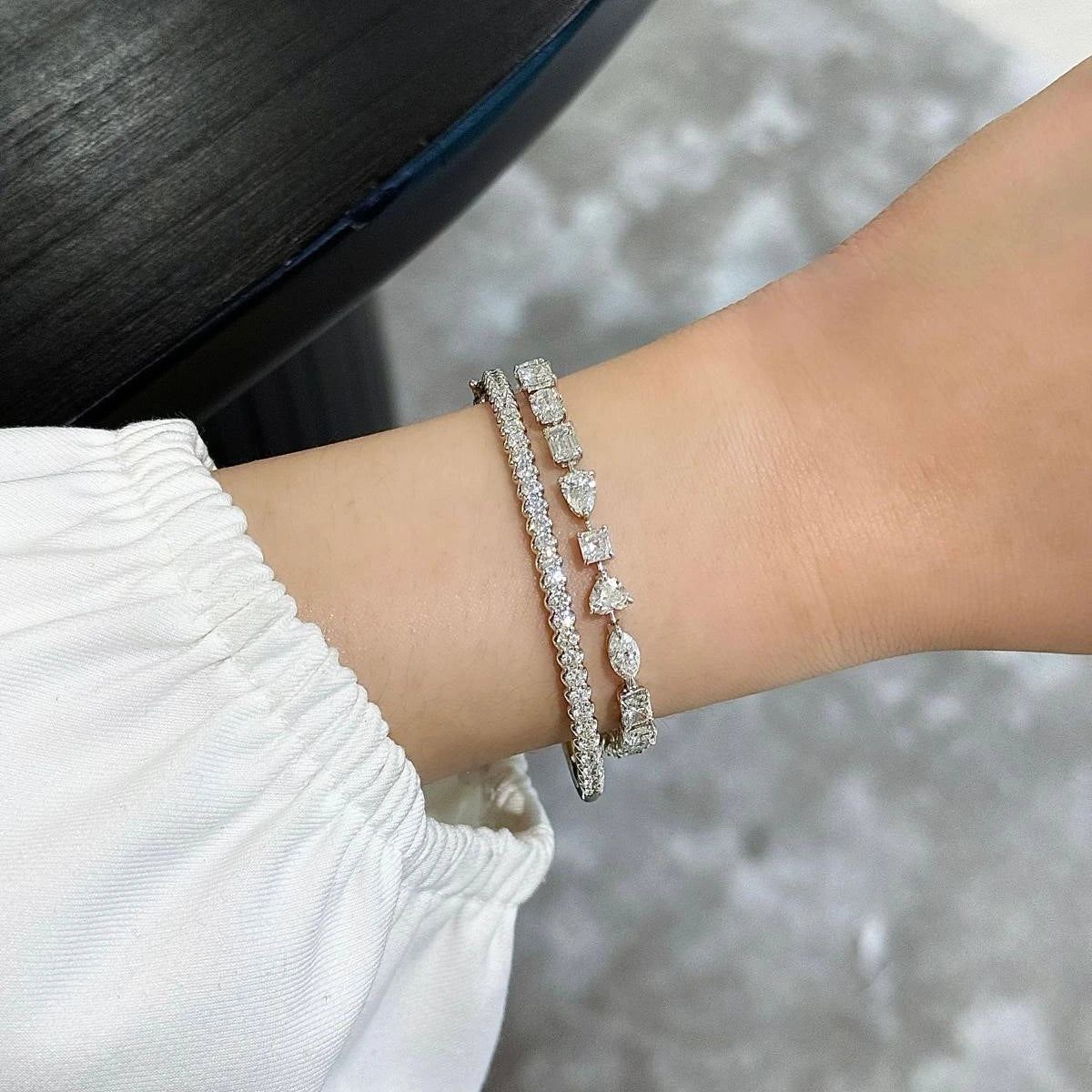 Close-up of a wrist wearing two diamond bracelets with a blurred background