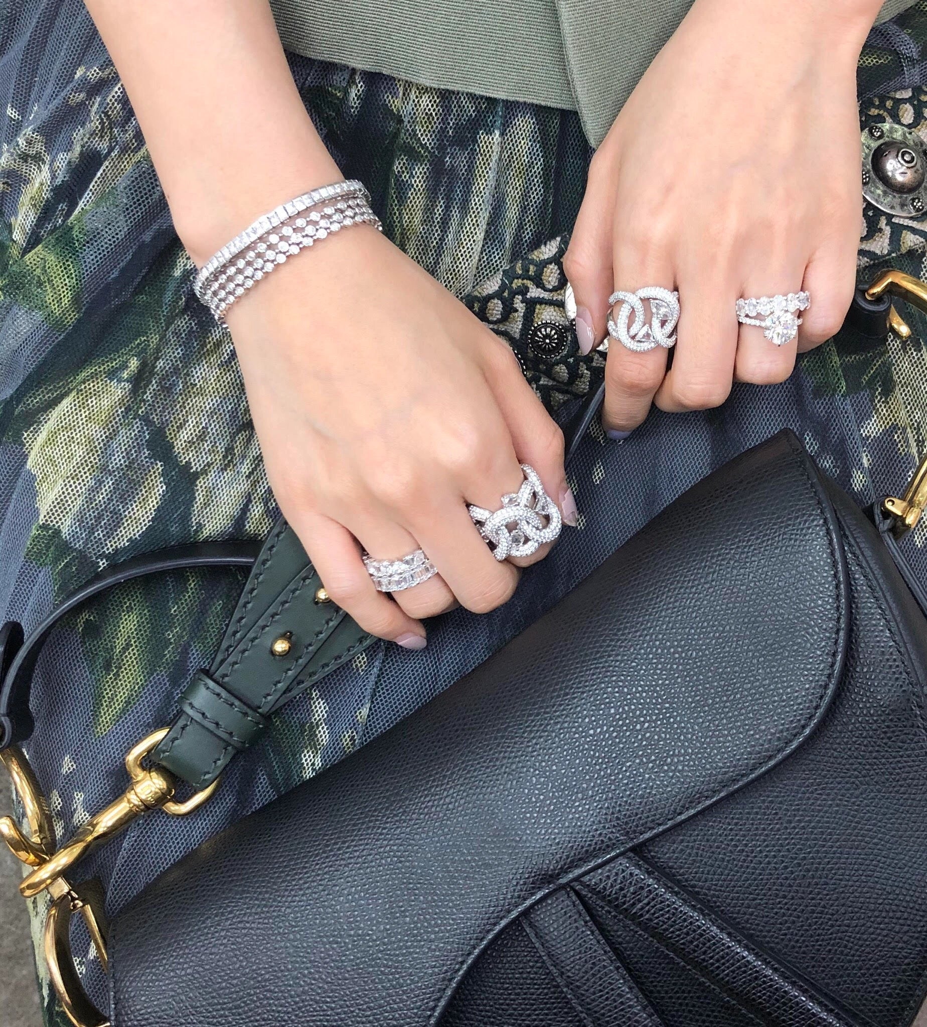 Close-up of hands with jewelry holding a black handbag