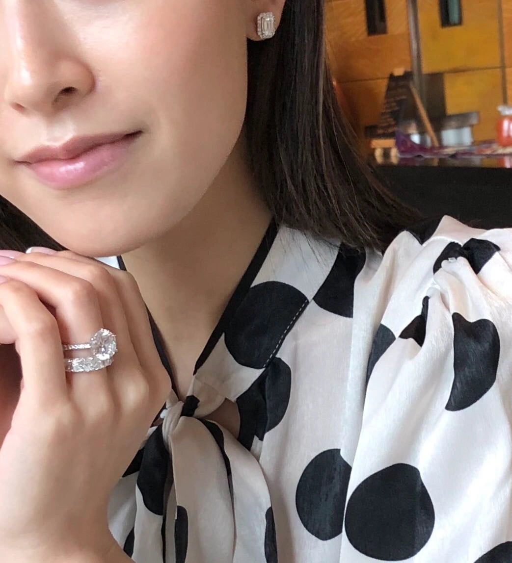 A person wearing a diamond ring and earrings.