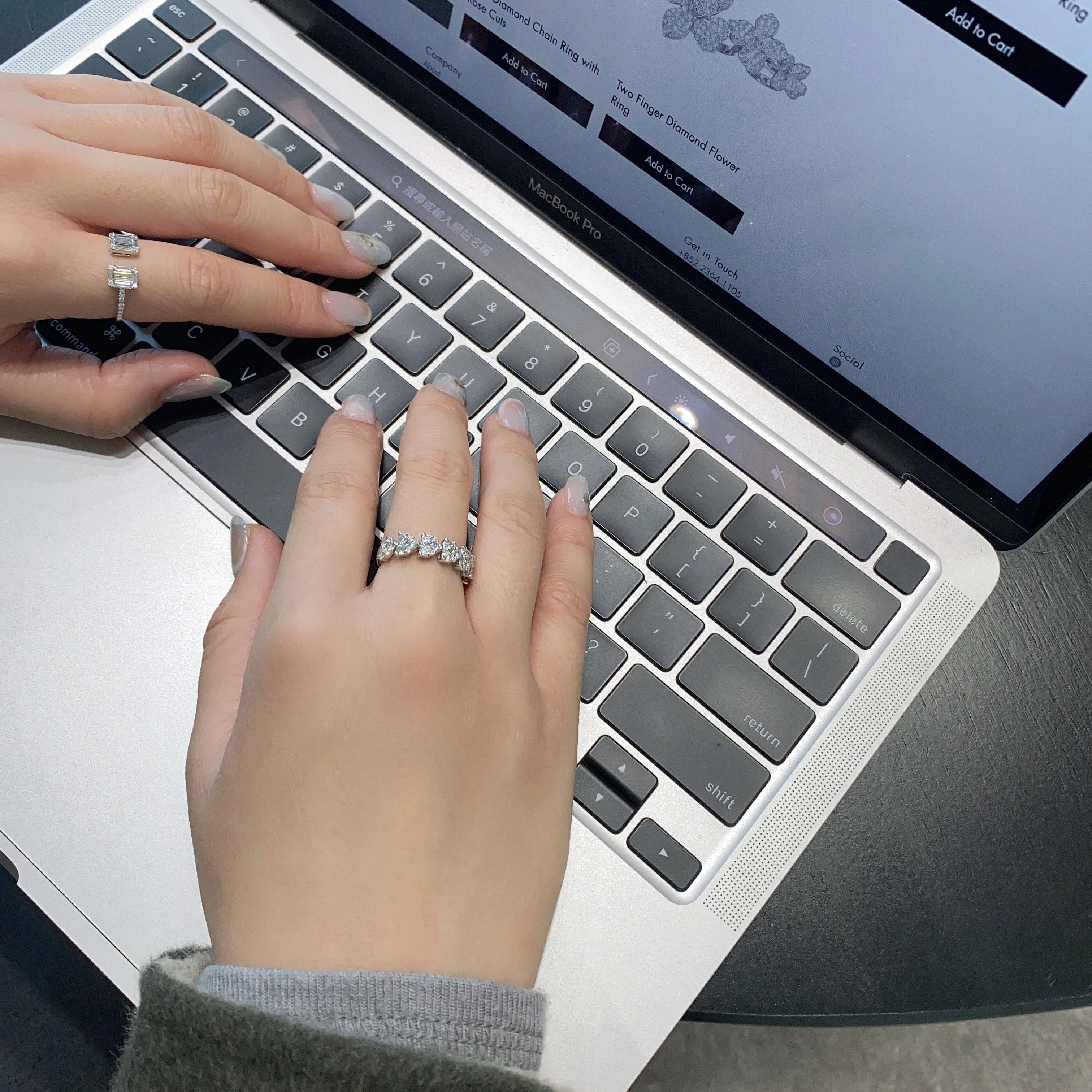 Person typing on a laptop with a focus on diamond rings