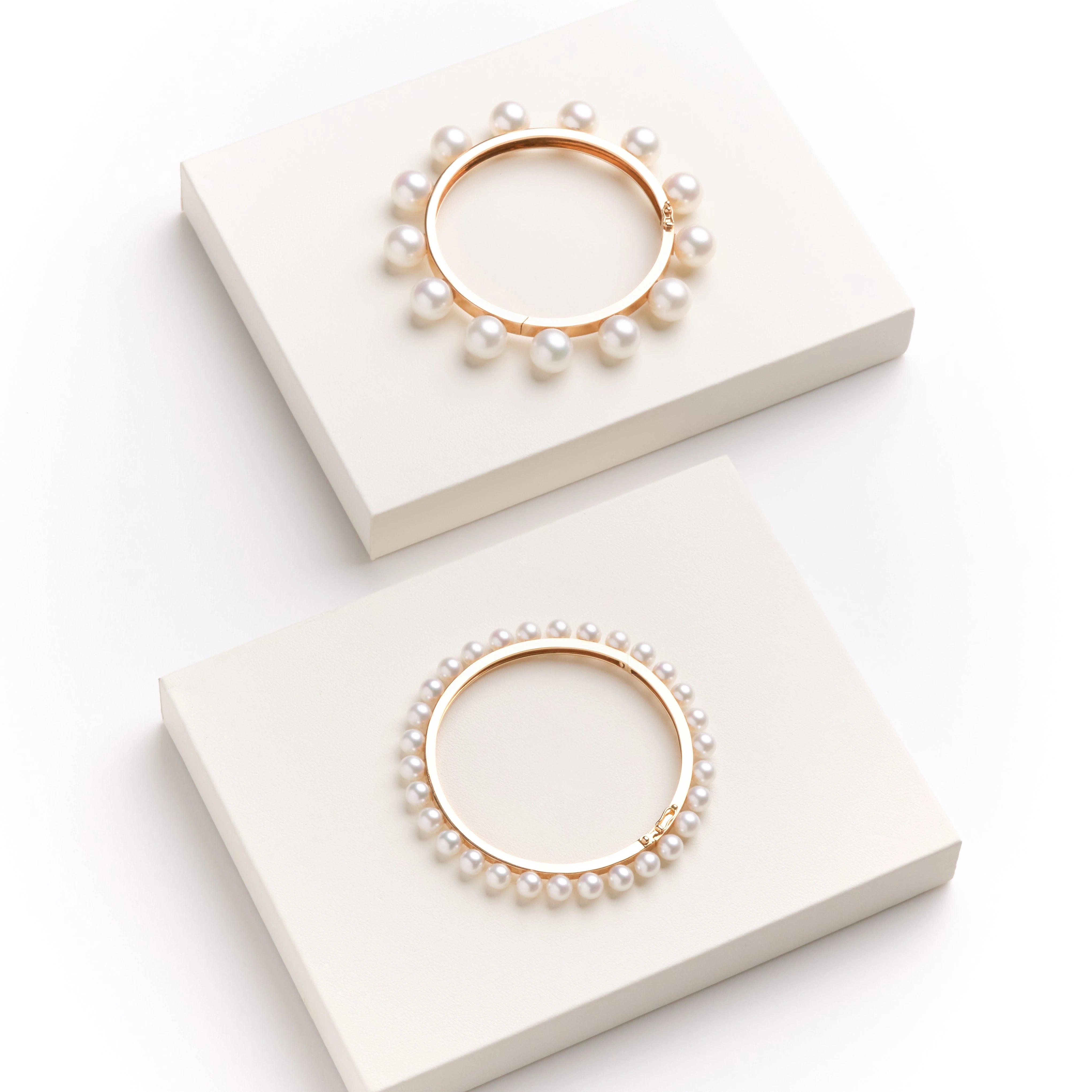 Two pearl bracelets on white display stands with a white background