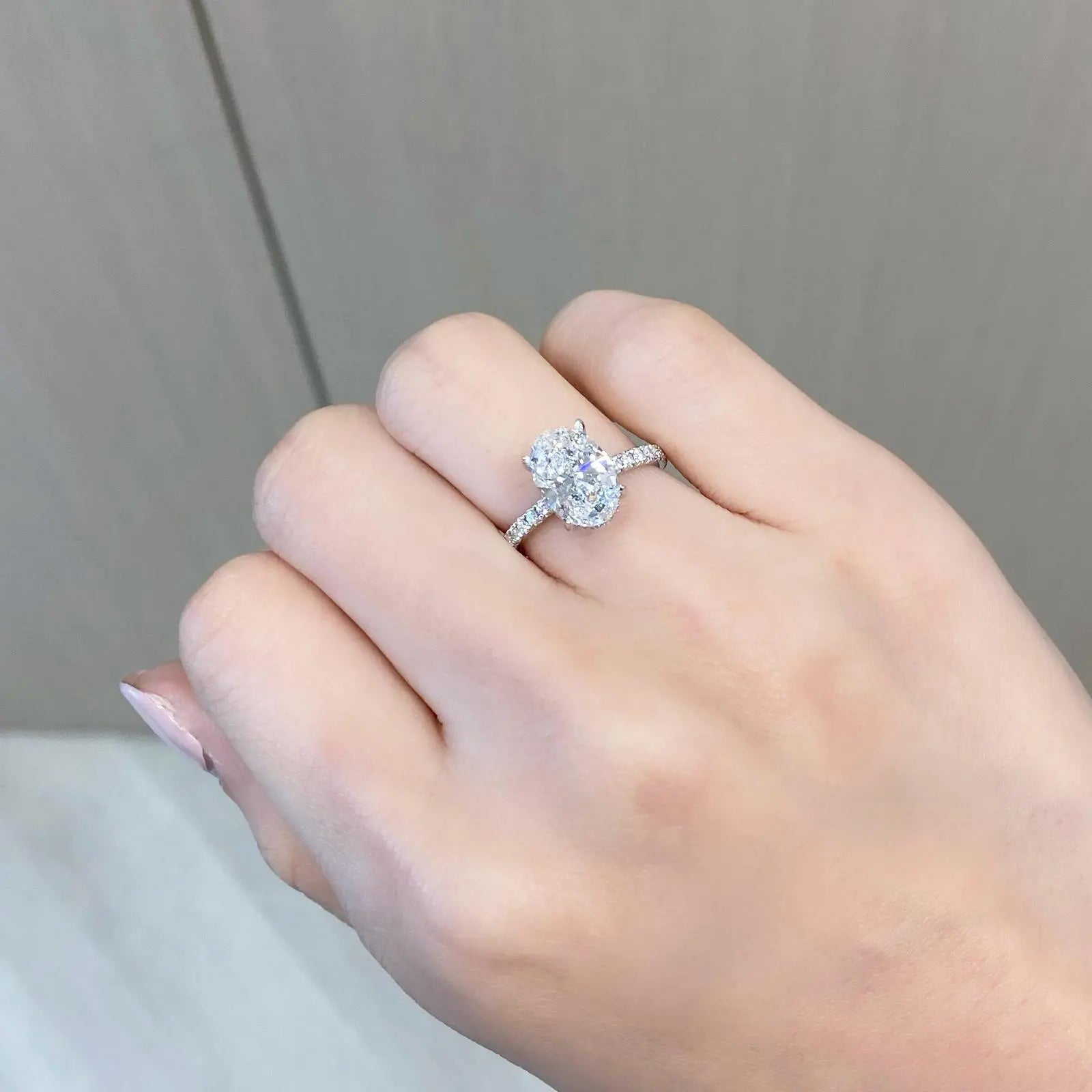Hand wearing a white gold oval engagement ring.