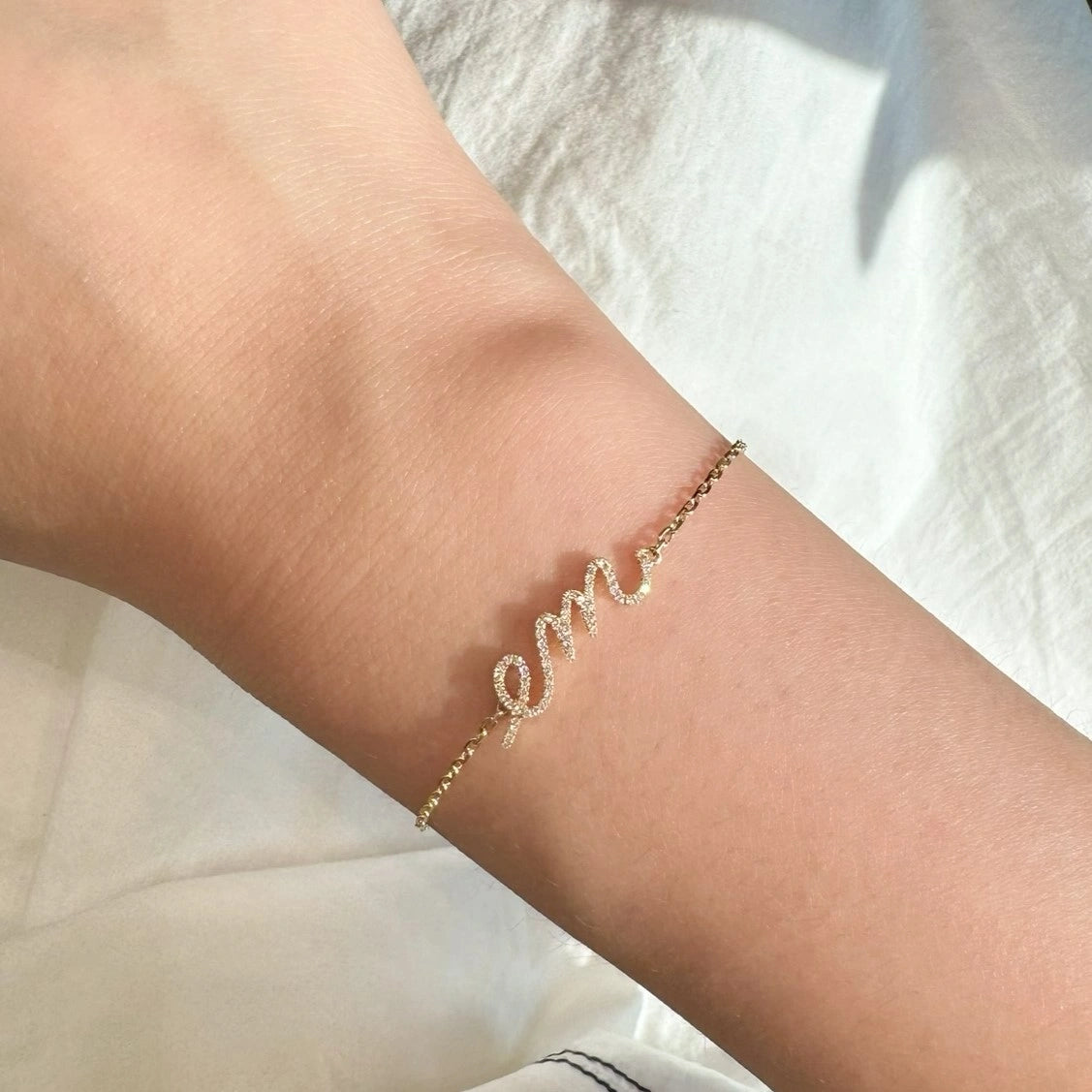Yellow gold bracelet with 'em' on a wrist against a white background
