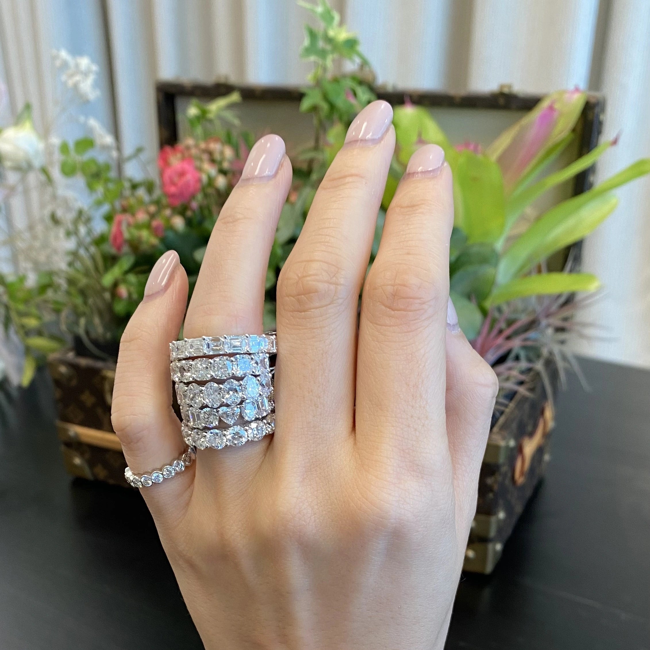 Hand wearing multiple diamond rings with a blurred indoor background