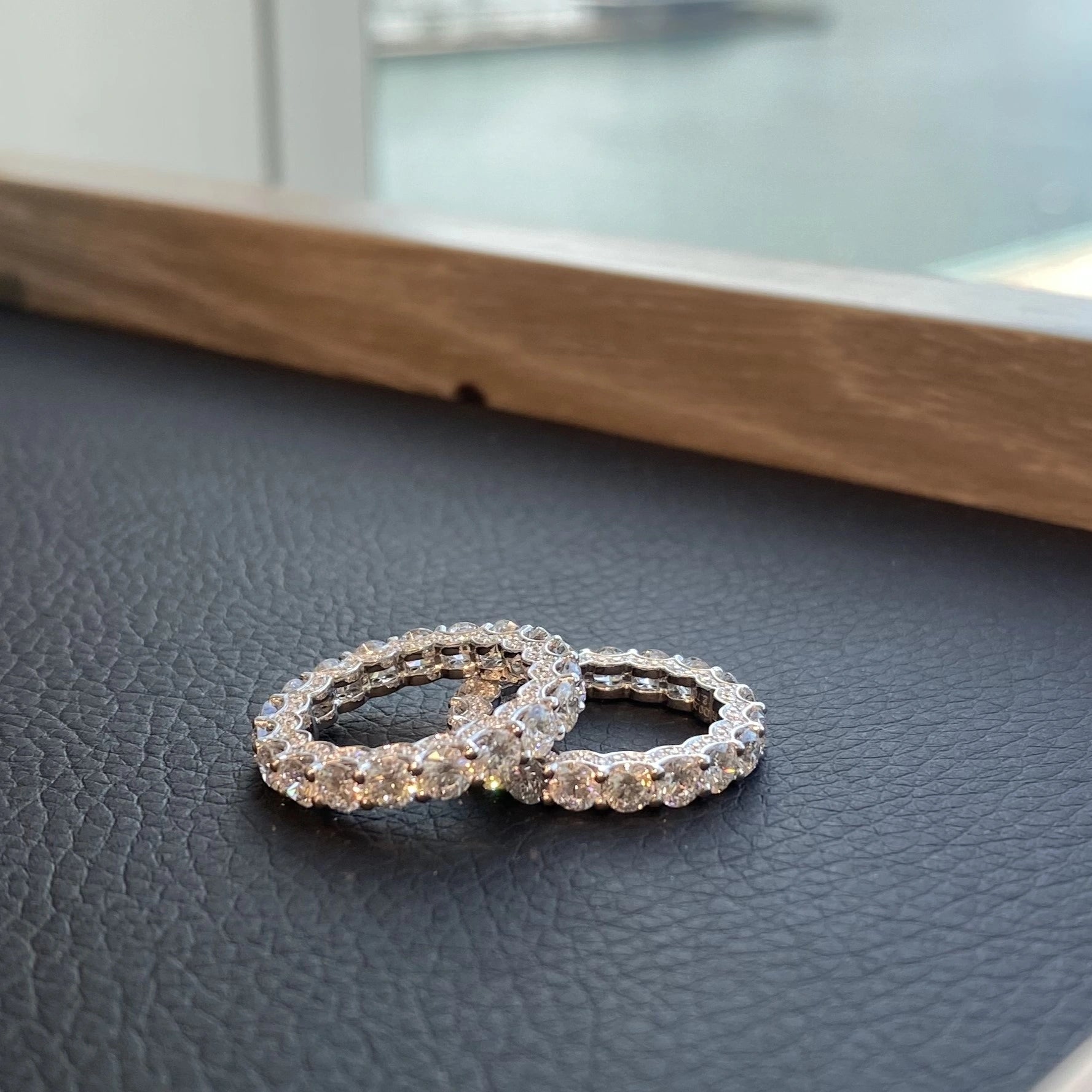 Two Eternity Rings on a dark surface.