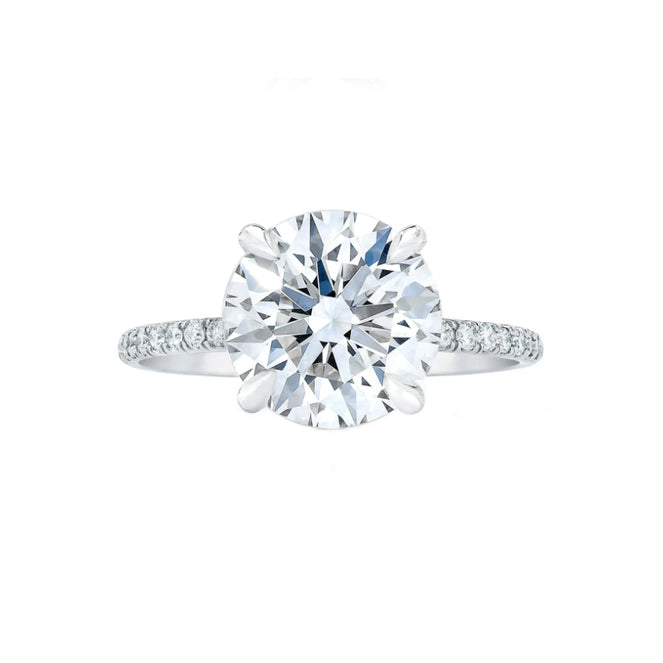 White gold signature four prong solitaire ring on white background.