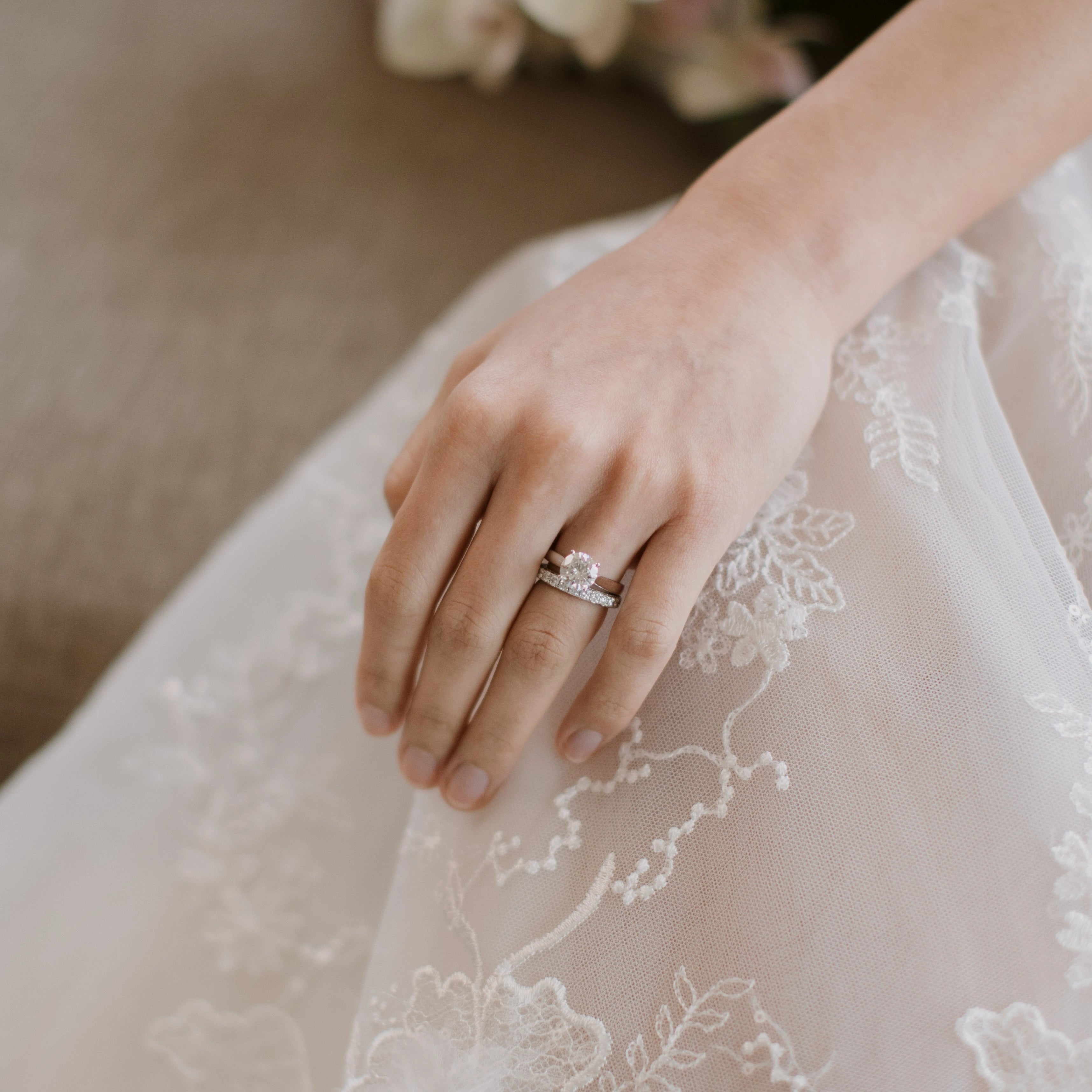 Hand wearing diamond ring on a lace garment
